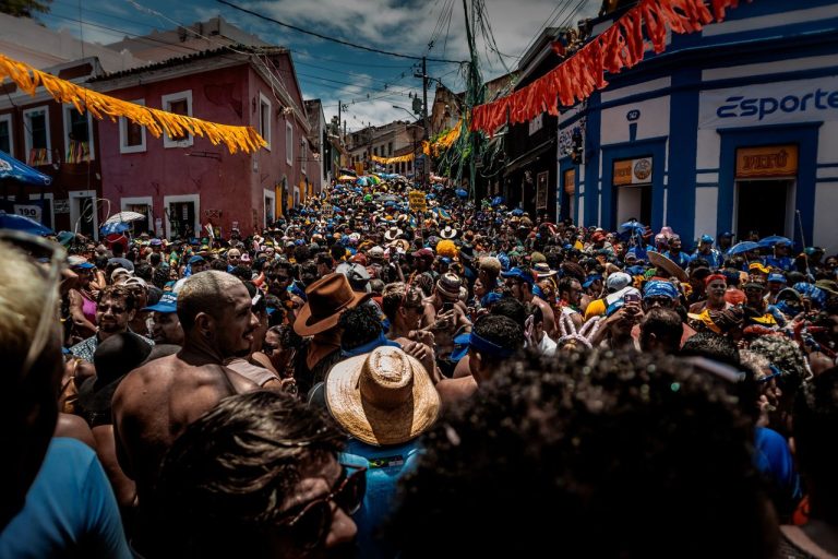 Multidão participa de uma festa de Carnaval de rua no Rio de Janeiro, cercada por adereços coloridos.